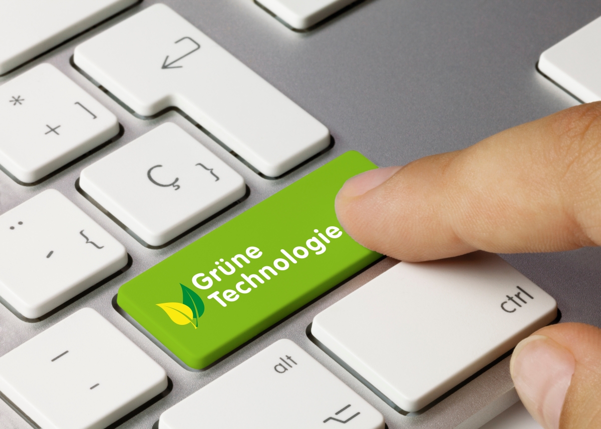 Blick auf eine Computertastatur - eine Hand drückt eine grün gefärbte Taste mit der Aufschrift "Grüne Technologie"